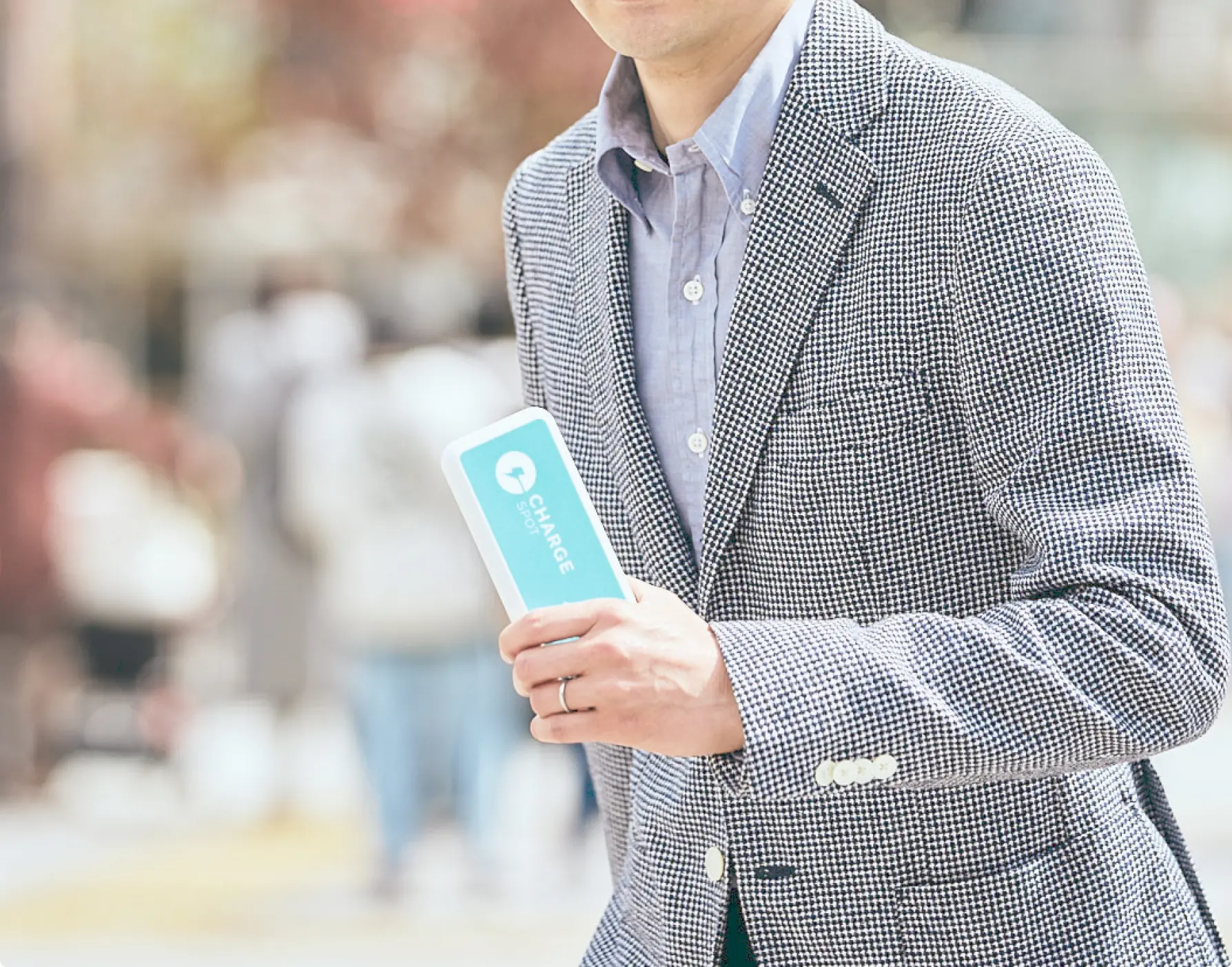 水色のモバイルバッテリーを持ったチェックのスーツを着た男性
