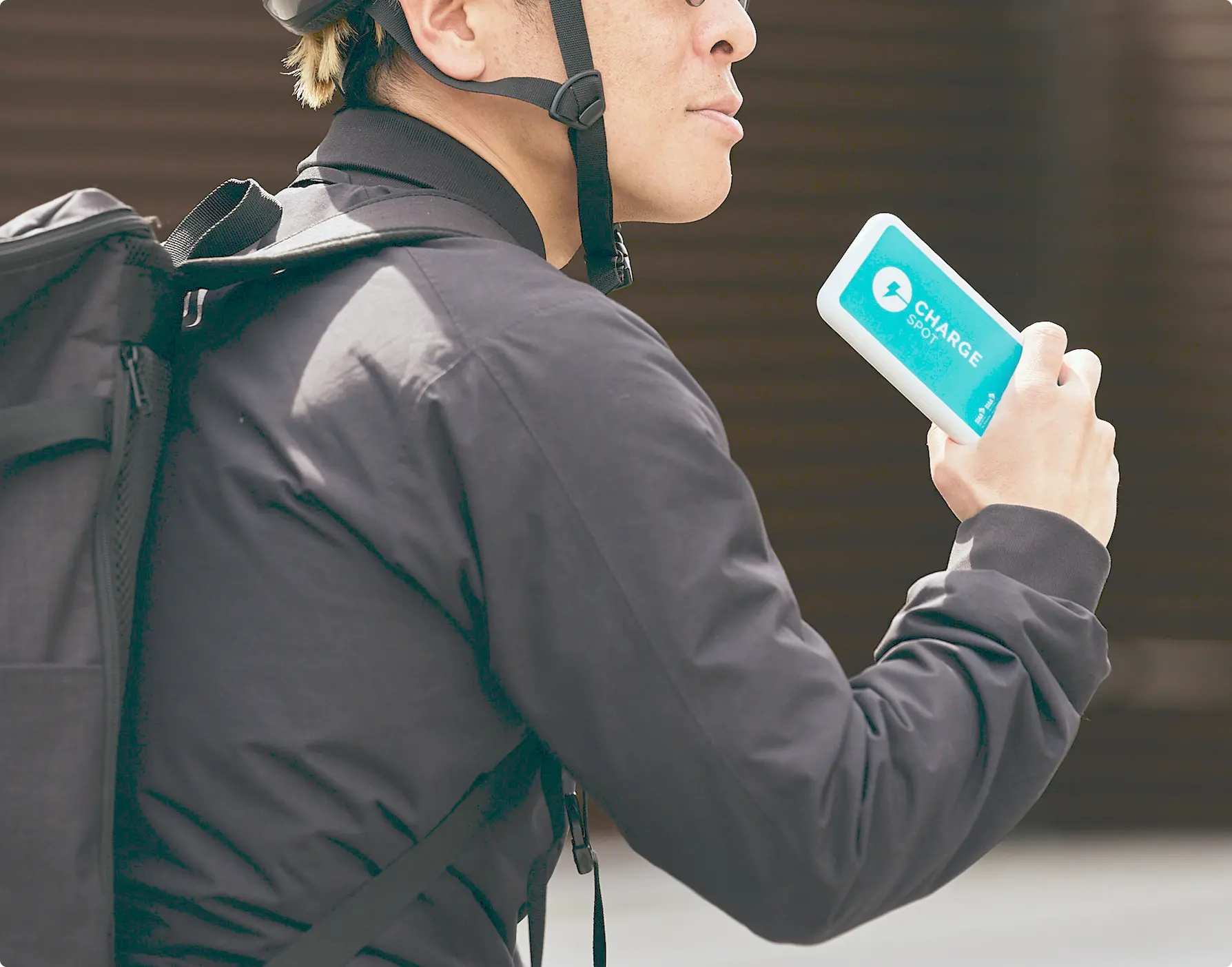 水色のモバイルバッテリーを持って自転車にまたがっている男性