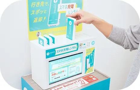 水色のモバイルバッテリーをチャージスポットに刺している男性