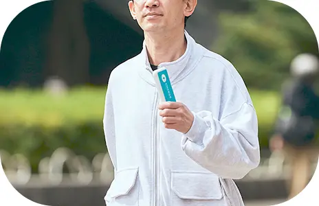 水色のモバイルバッテリーを持って散歩をしている男性